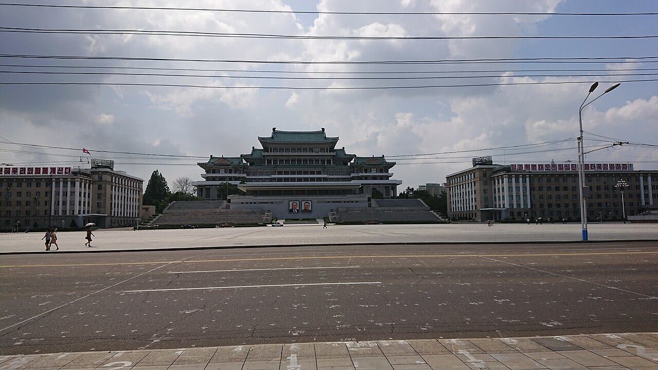 A vast, empty paved square in front of a large building with a traditional tiled roof.