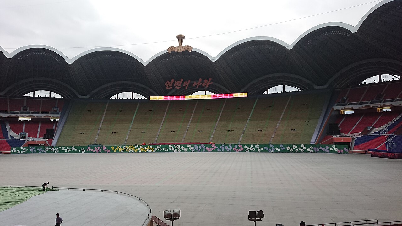 The inside of May Day Stadium, a vast field ringed by stands under a scalloped roof.