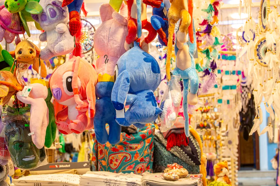 Stall crowded with hanging plush toys in bright colours.
