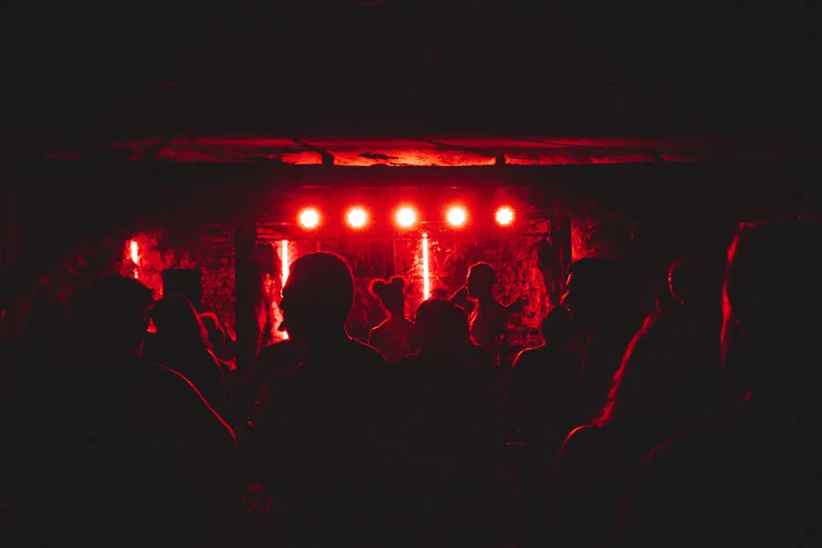 A dark crowd facing a stage washed in red light.